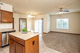 This single-floor residence offers a thoughtfully designed open-concept layout that seamlessly connects the kitchen, dining, and living areas. The kitchen is a functional centerpiece, featuring rich warm-toned wood cabinetry, generous counter space, a central island ideal for casual dining or meal prep, and a full suite of stainless steel appliances including a refrigerator, range, microwave, and dishwasher. Light wood-style flooring runs throughout the kitchen and dining area, transitioning to plush carpet in the living and bedroom spaces.

The living and dining area is bright and airy, benefiting from a sliding glass door that opens to a private balcony, allowing an abundance of natural light to fill the space. A ceiling fan keeps the area comfortable year-round. The bedrooms are well-sized with tall ceilings, soft carpeting, and windows that invite natural light. One bedroom includes a built-in closet with organized shelving. Two full bathrooms mirror one another in layout, each offering wood-style flooring, a vanity with cabinetry, and a tub-shower combination. Throughout the space, neutral wall tones and warm wood trim details create a clean, cohesive aesthetic that is both inviting and functional.