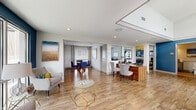 Located in Chattanooga, TN, this well-appointed single-floor community clubhouse offers a thoughtfully designed layout that blends functionality with modern style. The main entrance opens into a bright, airy lobby featuring soaring ceilings with clerestory windows that flood the space with natural light. Warm hardwood-style flooring, crisp white walls, and bold navy blue accent walls create a cohesive, contemporary aesthetic throughout.

The welcoming lounge area is furnished with stylish upholstered chairs, geometric gold-framed glass coffee tables, and floor-to-ceiling windows that provide panoramic views of the surrounding community. Adjacent to the lobby, a dedicated leasing office offers a professional workspace with ample room for consultations. A smaller private meeting room with a round glass table and blue chairs provides a quiet setting for one-on-one conversations.

The dining area features high clerestory windows, a substantial metal-topped communal table with industrial-style seating, and curated artwork that adds a creative touch. A fully equipped fitness center includes cardio machines, free weights, exercise balls, yoga mats, and a wall-mounted TV. A clean, accessible restroom with modern fixtures completes the facility. Throughout, the space maintains a polished yet inviting atmosphere ideal for community gatherings and daily resident use.