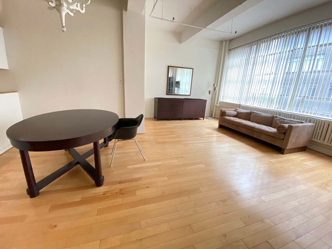 Large open space living/dining area with wall of south facing windows - 361 W 36th St