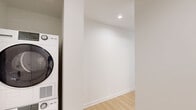 Located on the 10th floor of 351 Marin Blvd in Jersey City's vibrant waterfront district, this one-bedroom, one-bathroom residence offers a well-designed layout with a clean, contemporary aesthetic throughout. Light wood flooring runs continuously across the open-plan kitchen and living area, lending warmth and cohesion to the space.

The modern kitchen is a standout feature, outfitted with stainless steel appliances including a full-size refrigerator, electric range, and built-in microwave. Sleek gray cabinetry extends to the ceiling for ample storage, complemented by a quartz countertop island with an undermount sink. Large floor-to-ceiling windows frame striking views of the Jersey City skyline, flooding the space with natural light.

The living area continues the open, airy feel with expansive corner windows offering panoramic city views, creating an inviting and light-filled environment. The bedroom is a comfortable, well-proportioned room with its own large window overlooking the surrounding cityscape and light wood flooring throughout.

The bathroom is finished with large-format neutral floor tiles, a soaking tub, a wood-toned vanity with integrated sink, and a mirrored medicine cabinet, all set against clean white walls for a crisp, modern feel.