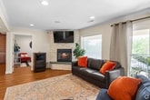 Located at 77 Barclay Place Ct in Charlottesville, VA, this single-floor space offers a thoughtfully designed layout across three distinct areas. The open living room is a standout feature, showcasing warm hardwood flooring, recessed lighting, and crown molding that adds a refined architectural touch. A striking stacked-stone fireplace serves as a focal point, flanked by a wall-mounted television, while structural columns define the space without interrupting the open flow. Large windows and a glass door at the far end of the living area flood the room with natural light and provide access to an outdoor balcony, enhancing the sense of openness. The kitchen is well-equipped with rich wood cabinetry, granite-style countertops, a tile backsplash, and black appliances including a refrigerator, range, and dishwasher. A built-in display niche with stone accents adds character to the kitchen and dining area. The adjacent dining space accommodates a full dining set and benefits from natural light through a window with plantation-style blinds. Throughout the space, consistent hardwood flooring and a neutral color palette create a cohesive, welcoming ambiance suited for both everyday use and gathering.