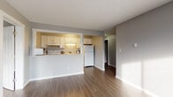 Located at 2136 West Riverside Avenue in Spokane, Washington, Unit 410 is a thoughtfully laid-out single-floor residence featuring a clean, modern aesthetic throughout. The open-concept living and dining area is anchored by durable wood-style flooring and neutral gray walls, with large windows that invite natural light and frame views of the surrounding treeline. A baseboard heating system ensures consistent comfort throughout the space.

The kitchen is positioned behind a half-wall pass-through counter, offering a functional and connected feel to the main living area. White shaker-style cabinetry, granite-look countertops, a double-basin sink, and full-size appliances — including a refrigerator, range, and microwave — provide everything needed for everyday living.

The bedrooms are generously proportioned, each featuring wood-style flooring, neutral walls, and wide windows with outdoor views. Ample closet space is available, with built-in shelving providing organized storage solutions. The bathroom is finished with a full tub and shower combo featuring white tile surround with decorative accents, a vanity with stone-look countertops, and modern fixtures.

A textured ceiling is consistent throughout the unit, complementing the clean, contemporary finishes. This well-maintained residence offers a comfortable and functional living environment in a convenient Spokane location.