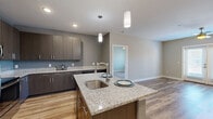 Located at 128 Florence St in Asheville, NC, this single-floor residence offers a thoughtfully designed layout with modern finishes throughout. The kitchen is a standout feature, showcasing dark wood cabinetry, granite countertops, stainless steel appliances, and a central island with a built-in sink and pendant lighting overhead — all set atop warm hardwood-style flooring that extends into the main living areas. The open living room is bright and airy, featuring French doors that invite natural light and a ceiling fan with track lighting above. The bedrooms are carpeted for comfort, with one room offering a window with natural light and a ceiling fan. A spacious walk-in closet with wire shelving systems provides generous storage. The bathrooms are finished with tile flooring, dark wood vanities, and white countertops. The primary bathroom includes a full tub-shower combo with white tile surround and direct access to the walk-in closet. A secondary bathroom features a framed mirror and clean, contemporary fixtures. Neutral wall tones and consistent modern detailing give the entire space a cohesive, move-in-ready aesthetic.