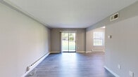 Located at 955 Easton Rd in Warrington, PA, this two-bedroom, one-bathroom residence offers a well-planned single-floor layout with modern finishes throughout. The combined kitchen and living area serves as the heart of the home, where luxury vinyl plank flooring in a soft gray tone flows seamlessly underfoot. The kitchen is appointed with stainless steel appliances — including a refrigerator, range, and microwave — complemented by two-tone cabinetry featuring white upper cabinets and dark lower cabinets, white countertops, and a tiled backsplash. The living room is bathed in natural light from a sliding glass door and multiple windows, all dressed with white blinds, that open to views of green, open outdoor space. A hallway connects the living area to the two bedrooms, each outfitted with hardwood-style flooring, neutral gray walls, a closet with bi-fold doors, and baseboard heating. The primary bedroom provides a comfortable, well-proportioned retreat. The bathroom features a full tub-shower combination with clean, large-format white tile surround. Throughout the residence, crisp white trim, neutral tones, and consistent flooring create a cohesive, move-in-ready aesthetic.