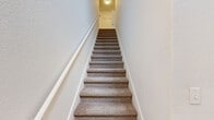 Located in Lady Lake, FL, this two-story, 2-bedroom, 2-bathroom home offers a well-organized layout spread across two levels. The main living floor is the heart of the home, featuring a generously sized open-plan living and dining area with soaring vaulted ceilings and a ceiling fan overhead. Soft carpeting runs throughout the living space, which is bathed in natural light from multiple windows and a sliding glass door that opens onto a private balcony overlooking lush greenery. The kitchen is thoughtfully designed in a galley style, featuring granite countertops, a stainless steel sink, stainless steel appliances including a refrigerator and dishwasher, white upper cabinetry, and light tile flooring. Both bathrooms are finished with tile flooring, granite-topped vanities, and full soaking tub and shower combinations. The two bedrooms are carpeted and filled with natural light from large windows. The spacious primary bedroom provides a comfortable retreat. A carpeted staircase with white trim connects the entry-level foyer to the main living floor above. Two closets provide ample storage throughout the home. The bright, neutral palette and consistent finishes create a clean and cohesive ambiance throughout.