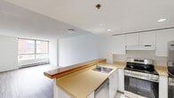 Located at 178 Rue Charlotte in Montréal's vibrant urban core, this well-appointed one-bedroom, one-bathroom unit offers a clean and functional layout across a single floor. The open-concept kitchen and living area forms the heart of the space, where a warm butcher-block breakfast bar serves as a natural divider. The kitchen is outfitted with crisp white cabinetry, stainless steel appliances including a refrigerator and range, and recessed lighting that keeps the area bright and practical. The living area flows seamlessly from the kitchen, featuring light wood-tone flooring and a large window that draws in natural light and frames views of the surrounding neighbourhood. The generously sized bedroom offers a comfortable retreat, with the same light wood flooring, a full-width mirrored sliding closet for ample storage, and a large window providing additional natural light. The bathroom is finished with light tile flooring, a vanity with under-sink storage, a dark countertop, and a wide mirror. Throughout the unit, a consistent white palette and clean lines create a bright, neutral ambiance that is both modern and easy to personalize. Baseboard heating is present in key areas, ensuring comfort year-round.