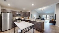 Located at 9060 Heirloom Ln. in Reynoldsburg, Ohio, this single-floor, 2-bedroom, 2-bathroom home offers a thoughtfully designed layout with modern finishes throughout. The open-concept kitchen and living area serves as the heart of the home, featuring dark espresso cabinetry, granite countertops, stainless steel appliances, and wood-look plank flooring. A kitchen island provides additional workspace and casual seating. The living room benefits from vaulted ceilings and a ceiling fan, creating an airy, spacious atmosphere with access to a balcony.

The primary bedroom is a generously sized retreat with plush carpeting and direct access to a walk-in closet equipped with wire shelving systems. The bathrooms are finished with granite vanity tops, dark cabinetry, and striking marble-style tile flooring. A dedicated laundry room accommodates a full-size washer and dryer with added shelving for storage.

A hallway connects the living areas to both bedrooms, maintaining a practical flow. The attached garage offers ample space for parking and additional storage. Overall, the home presents a clean, contemporary aesthetic with cohesive finishes and functional spaces throughout.