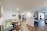 This thoughtfully designed one-bedroom, two-bathroom residence at 1 Ridge Rd in Auburn, Massachusetts offers a comfortable and modern living experience across a well-proportioned single floor. The open-concept kitchen and living area serves as the heart of the home, featuring white shaker cabinetry, granite countertops, stainless steel appliances including a French door refrigerator and range, and a cozy dining nook — all tied together by warm hardwood-style flooring that flows throughout the unit. The living room is anchored by a distinctive board-and-batten accent wall with an elegant oval mirror, creating a refined focal point. A second living area offers additional flexibility, filled with natural light from a large window overlooking the outdoors. The spacious bedroom features dual windows that invite abundant natural light and outdoor views, providing a serene retreat. Both bathrooms are well-appointed with granite vanities and white cabinetry; one includes a full soaking tub with shower. Clean white walls, consistent flooring, and a neutral palette lend the space a cohesive, modern aesthetic throughout.