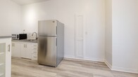 Located at 323 E Lomita Ave in Glendale, California, this two-bedroom, one-bathroom single-floor unit offers a clean, minimalist aesthetic throughout. Light wood-style laminate flooring runs consistently across the living spaces, lending a bright and cohesive feel to the interior.

The spacious primary bedroom is notably generous in size, featuring crisp white walls, a ceiling fan with integrated lighting, and a wall-mounted heating unit. Natural light filters in through multiple windows fitted with blinds, creating an airy and comfortable environment. The second bedroom is more compact, also finished with the same light flooring, white walls, and a ceiling fan.

The kitchen is efficiently laid out, featuring white cabinetry with a display cabinet, a gas range, stainless steel refrigerator, and a sink with brushed nickel hardware. Track lighting above illuminates the galley-style layout, which connects conveniently to the rest of the unit via a hallway.

The bathroom is a standout, showcasing retro-style teal ceramic wall tiles accented with black border tiles — a charming vintage detail. It includes a bathtub, toilet, and vanity, with a window providing natural ventilation. The overall unit presents a clean, move-in-ready space with a blend of classic character and updated finishes.