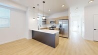 This well-designed three-story home offers five bedrooms and four bathrooms, thoughtfully distributed across each level to maximize privacy and functionality. Light wood flooring flows consistently throughout, complementing the clean white walls and modern aesthetic visible in every room.

The open-concept kitchen and living area serves as the heart of the home, featuring a large central island with a dark base and white quartz countertop, stainless steel appliances, warm wood cabinetry, and globe pendant lights that add a contemporary touch. Sliding glass doors in one of the main rooms open to a patio, inviting natural light and outdoor access.

The bedrooms are bright and airy, each benefiting from natural light through blinded windows. The spacious primary bedroom includes direct patio access. With nine closets throughout, storage is abundant on every floor. The bathrooms maintain the home's modern character, featuring wood-toned vanities, matte black fixtures, and tub-shower combinations.

A dedicated laundry room with a window adds convenience, while three staircases with light wood treads and sleek metal handrails connect the floors with style. Hallways and transition spaces are clean and uncluttered, reinforcing the home's minimal, contemporary design throughout.