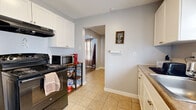 Located at 425 W Tennessee St in Florence, Alabama, this single-floor 1-bedroom, 1-bathroom home offers a thoughtfully arranged layout with a warm and welcoming atmosphere. The kitchen is well-appointed with white cabinetry, a black electric range with overhead ventilation, a stainless steel refrigerator, and tile flooring. A double sink sits beneath natural light from dual windows, and a utility shelf provides additional storage and counter space. The kitchen flows through an arched passageway into the dining area, which features tile flooring and comfortably seats six. The living room is a bright, relaxed space with wood-look plank flooring, a ceiling fan, and large windows dressed in sheer curtains that allow generous natural light. The bedroom continues the rustic aesthetic with wood-look flooring, a reclaimed-wood bed frame, matching dresser and nightstand, and a window with natural light. The full bathroom includes a tub-shower combo with tile surround and a striped curtain, paired with a pedestal sink and tile flooring. Throughout the home, soft gray walls and warm wood tones create a cohesive, cozy ambiance well-suited for comfortable living in Florence, AL.