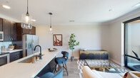 This thoughtfully designed single-floor residence combines modern aesthetics with functional living spaces. The entryway welcomes you with warm wood-look flooring, neutral tones, and a clean, minimalist feel that sets the tone for the rest of the home.

The open-concept kitchen is a standout feature, outfitted with rich dark-stained cabinetry that extends to the ceiling, stainless steel appliances including a side-by-side refrigerator and electric range, a white quartz countertop island with an undermount sink, and stylish pendant lighting overhead. The kitchen flows seamlessly into the living and dining area, creating an ideal space for entertaining.

The living room is bright and airy, anchored by floor-to-ceiling black-framed sliding glass doors that open to a balcony and frame expansive views of a waterway and surrounding greenery, filling the space with abundant natural light.

The bedroom continues the serene atmosphere with soft, neutral walls, plush carpeting, and large windows offering the same impressive waterfront views. Thoughtful lighting fixtures and generous wall space complete the room.

The bathroom features wood-look tile flooring, a dark wood vanity with a white countertop, and warm neutral wall tones that create a calm, spa-like ambiance. Throughout the residence, cohesive finishes and contemporary design elements create a polished, inviting living environment.