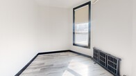 Located at 260 Sherbourne Street in Toronto's vibrant Cabbagetown neighbourhood, this one-bedroom, one-bathroom unit offers a thoughtfully utilized layout across a single floor. The space has been updated with modern finishes throughout, creating a clean and contemporary aesthetic.

The kitchen is a standout feature, outfitted with sleek white gloss cabinetry extending to the ceiling for maximum storage, dark countertops, a subway tile backsplash, and stainless steel appliances including a refrigerator and range. Light wood-style flooring runs through the main areas, complemented by bold dark baseboards that add a sharp visual contrast. An overhead chandelier-style light fixture adds a touch of character to the kitchen area.

The bedroom is a bright, cozy room featuring a large window with a roller blind that allows natural light to filter in. A cast iron radiator adds a charming, heritage touch, nodding to the building's classic character. The walls are finished in crisp white, keeping the room feeling open and airy.

The bathroom is finished with classic white subway tile on the walls, neutral stone-look floor tiles, and a full bathtub, offering a clean and functional space. Overall, this unit blends modern renovations with subtle heritage details, making it a well-appointed option in central Toronto.