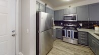 Located at 34 Woodcross Dr in Columbia, South Carolina, this single-floor home offers a well-designed layout with a variety of comfortable living spaces. The kitchen is a standout feature, equipped with stainless steel appliances including a refrigerator, range, and microwave, complemented by gray shaker-style cabinetry, granite-look countertops, a dark subway tile backsplash, and durable wood-look flooring. A breakfast bar connects the kitchen to the open living and dining area, which is finished with plush carpeting, a pendant light fixture, and a door providing direct outdoor access with natural light streaming through adjacent windows. The bedrooms are generously proportioned, each featuring soft carpeted floors, ceiling fans with light kits, natural light from windowed walls with blinds, and closet access via classic panel doors. The bathroom includes a full tub and shower combination with built-in shelving and chrome fixtures, alongside a vanity with a single-basin sink, gray cabinetry, a large mirror, and updated brushed nickel hardware. Textured ceilings and neutral-toned walls throughout the home create a cohesive and understated aesthetic, making this a practical and comfortable residence in the Columbia area.