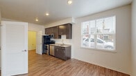 This well-designed 2-bedroom, 2-bathroom single-floor unit offers a practical and modern layout with thoughtful finishes throughout. The open kitchen and living area serves as the heart of the home, featuring dark espresso cabinetry with brushed nickel hardware, stainless steel appliances including a range, microwave, and dishwasher, and a single-basin sink with a modern faucet. Wood-look plank flooring extends seamlessly throughout the entire unit, adding warmth and visual continuity.

The living room is a bright, inviting space highlighted by a built-in fireplace with a clean white surround, a ceiling fan with light fixture, and large windows dressed with horizontal blinds that allow ample natural light while maintaining privacy. An exterior door provides additional access and light to the living area.

The bedrooms are well-proportioned and bright, each featuring windows with blinds. The primary bedroom offers a comfortable footprint suited for a full bedroom set. The two bathrooms are clean and functional, with one featuring a walk-in shower unit with a built-in seat and brushed nickel fixtures, and the other offering a vanity with dark wood cabinetry. An in-unit washer is also included, adding everyday convenience to this efficiently organized space.