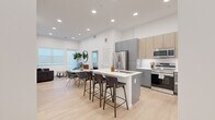 This well-appointed 2-bedroom, 2-bathroom residence combines modern design with functional living across a single floor. The open-concept kitchen, dining, and living area serves as the heart of the home, featuring high ceilings with recessed lighting and light wood-style flooring that enhances the bright, airy atmosphere. The kitchen is outfitted with stainless steel appliances, a mix of gray and natural wood cabinetry, a white quartz countertop, and a central island with bar seating — ideal for both everyday meals and entertaining. The living area benefits from large windows with roller shades, allowing ample natural light to fill the space. Both bedrooms are carpeted and well-lit with natural light from sizable windows. The primary bedroom offers generous proportions and direct access to a dedicated closet. A second bedroom provides a comfortable and versatile space. Each bathroom is finished with gray cabinetry, white quartz vanity tops, large mirrors, and light wood-style flooring. One bathroom features a shower-tub combo, while the other offers an elongated double-sink vanity. Two closets provide practical storage throughout the residence, including a spacious walk-in closet with wire shelving.