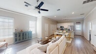 Located at 9913 Crescent Harbor Dr in Montgomery, TX, this two-story home presents a well-designed layout with a cohesive, light-filled aesthetic throughout. The main living area features an open-concept floor plan where the living room flows seamlessly into the dining area and kitchen. Wide-plank hardwood-style flooring, crown molding, and ceiling fans contribute to the space's polished yet relaxed character. Multiple windows allow natural light to fill the room, complementing the neutral color palette.

The kitchen is a functional centerpiece, equipped with white shaker-style cabinetry extending to the ceiling, granite countertops, a tile backsplash, stainless steel appliances, and a large island with an undermount sink. Track lighting overhead adds focused illumination throughout.

The primary bedroom is generously proportioned, featuring elevated ceilings, a ceiling fan, plush carpeting, and access to a spacious walk-in closet with built-in shelving. An additional room serves well as a home office, with carpeted floors and natural light from a window. Bathrooms include tile flooring, granite vanity tops, and a tub-shower combination. A convenient powder room with tile flooring is also present. The walk-in closet offers extensive shelving and hanging space, maximizing storage capacity.