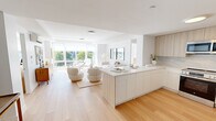 Located at 1 Lyon Place, Unit 5A in White Plains, NY, this well-appointed 2-bedroom, 2-bathroom residence offers a thoughtfully designed single-floor layout with a clean, modern aesthetic. The open-concept living and kitchen area serves as the heart of the home, featuring light hardwood floors, crisp white walls, and expansive floor-to-ceiling windows that flood the space with natural light and frame outdoor views of the surrounding neighborhood. The kitchen is outfitted with flat-front cabinetry in a warm wood tone, a marble-style backsplash, stainless steel appliances, and a generous island with ample storage. The living area flows seamlessly into a dedicated dining room, which offers an intimate setting with hardwood flooring and white walls ideal for displaying artwork. Both bedrooms are bright and airy, benefiting from large windows with outdoor views and individual wall-mounted climate control units. The generously sized primary bedroom provides a serene retreat with abundant natural light. Both bathrooms share a consistent design language, featuring warm wood vanities, large-format tile flooring, and striking marble-clad tub and shower surrounds that add a refined, upscale touch to the overall space.