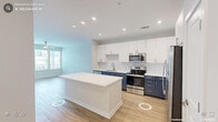 Located in Cary, NC, this well-appointed one-bedroom, one-bathroom residence offers a thoughtfully designed single-floor layout with modern finishes throughout. Light hardwood-style flooring flows seamlessly across the entire space, lending warmth and visual continuity to every room.

The open-concept kitchen and living area serves as the heart of the home. The kitchen is outfitted with a striking two-tone design, pairing crisp white upper cabinetry with deep navy lower cabinets, complemented by a classic white subway tile backsplash. A large center island with a white countertop provides ample prep space and casual seating. Stainless steel appliances, including a range, microwave, refrigerator, and dishwasher, complete the functional and stylish kitchen suite. Natural light from oversized windows brightens the adjacent living area.

The spacious bedroom features windows that frame outdoor views and includes a ceiling fan for year-round comfort. Two closets — including a generously sized walk-in closet with built-in wire shelving systems — offer excellent storage capacity.

The full bathroom is finished with a navy vanity, white countertop, large frameless mirror, and a tiled shower-tub combination, maintaining the cohesive modern aesthetic found throughout the residence.