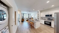 Located at 19815 Kenswick Drive in Humble, TX, this single-story residence offers a thoughtfully designed open-concept layout that seamlessly connects the kitchen, dining, and living areas. Light wood-style flooring runs throughout, contributing to a cohesive and airy aesthetic.

The kitchen is a standout feature, equipped with white shaker cabinetry, granite countertops, stainless steel appliances including a french door refrigerator, electric range, microwave, and dishwasher. A large center island with a built-in sink provides additional prep space and casual seating for two. Open shelving nearby adds both functionality and visual interest. A stacked washer and dryer unit is conveniently located just off the kitchen.

The living area benefits from natural light through a large window and is finished with a ceiling fan overhead. The bedroom is generously proportioned, featuring light-filled windows, wood-style flooring, and access to a well-appointed bathroom with granite countertops, white cabinetry, and a wide vanity mirror. A walk-in closet with wire shelving provides practical storage. The overall design is clean and modern, with a neutral palette that creates a bright, welcoming atmosphere throughout.