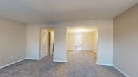 Located at 2112-A Criston Dr in Newport News, Virginia, this two-story home offers four bedrooms and three bathrooms across a well-organized floor plan. The main level features a carpeted living room that opens into a dining area adorned with a chandelier, creating a bright and connected gathering space. The kitchen is equipped with dark espresso cabinetry, granite-style countertops, stainless steel appliances including a refrigerator and dishwasher, and wood-look flooring, with a window that brings in natural light. A hallway on the main floor leads to additional rooms and provides access to a dedicated laundry closet housing a full-size washer and dryer unit with overhead shelving. The staircase, featuring a warm wood banister and white balusters, connects to the upper level, where the remaining bedrooms and bathrooms are located. The generously sized primary bedroom receives ample natural light and includes a walk-in closet with a full-length hanging rod. Bathrooms are outfitted with tiled tub-shower combinations. Neutral wall tones and plush carpet throughout the bedrooms and living areas give the home a clean, move-in-ready feel. The layout is practical and well-suited for everyday living.
