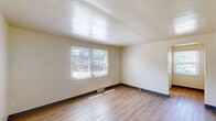 Located at 165 Princeton Avenue in Buffalo, NY, this single-floor unit offers three bedrooms, one bathroom, a kitchen, and a hallway across a compact and efficiently arranged floor plan. Warm-toned hardwood-style flooring runs consistently throughout the space, giving the interior a cohesive and clean aesthetic.

The primary bedroom is the most spacious of the three, offering ample room for furnishings. Each bedroom features neutral cream-colored walls, blinds-fitted windows that provide natural light and views of surrounding greenery and neighborhood scenery, and built-in closet storage. The secondary bedrooms are more intimate in scale but maintain the same bright, functional character.

The kitchen is equipped with a white range and wood-toned cabinetry, providing practical storage and workspace. A window above or near the kitchen brings in additional natural light and outdoor views.

The bathroom is cleanly finished in white, featuring a wall-mounted sink, toilet, and a shower-tub combination with a curved curtain rod. A frosted window allows natural light while maintaining privacy.

Throughout the unit, dark baseboards provide a subtle contrast to the light walls and flooring. Floor vents are present in multiple rooms for heating. The overall ambiance is straightforward and functional, making it a practical living space in the Princeton Avenue neighborhood of Buffalo.
