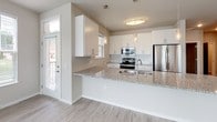 Located at 6616 Century Ave in Middleton, Wisconsin, this single-floor residence offers a thoughtfully designed layout with contemporary finishes throughout. The open-concept living and kitchen area is a standout feature, anchored by light wood-look flooring, a ceiling fan, and multiple windows that invite generous natural light and views of the surrounding neighborhood. The kitchen is well-appointed with white shaker-style cabinetry, a white subway tile backsplash, stainless steel appliances including a refrigerator, electric range, and microwave, as well as a granite-topped peninsula that provides both workspace and casual seating. Pendant lighting and a flush-mount ceiling fixture complement the kitchen's clean, modern aesthetic. The bedrooms feature neutral-toned carpet, ceiling fans, and windows with blinds that allow for natural light while maintaining privacy. The bathrooms are finished with granite countertops, white vanity cabinetry with brushed nickel hardware, large framed mirrors, and wood-look tile flooring, offering a cohesive and polished look. Neutral wall tones and consistent trim details carry throughout the space, creating a calm and cohesive atmosphere well-suited for everyday living.