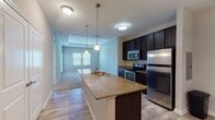 Located at 1533 Ellis Rd in Durham, NC, this single-floor residence offers a thoughtfully designed layout that balances open communal spaces with comfortable private retreats. The kitchen serves as a central hub, featuring dark espresso cabinetry, granite countertops, a peninsula island with a built-in sink, pendant lighting, and a full suite of stainless steel appliances including a refrigerator, range, and microwave. Wood-look flooring extends through the kitchen and dining area, while the living space transitions to plush carpeting, creating a warm and inviting atmosphere. Natural light flows throughout via multiple windows dressed with blinds. The bedrooms are generously proportioned, carpeted, and well-lit, with one featuring a tray ceiling detail that adds architectural interest. The bathrooms echo the kitchen's design aesthetic, showcasing dark vanity cabinetry, granite countertops, and tile-surround soaking tubs. At least one bedroom benefits from an en-suite bath, offering added convenience and privacy. The neutral color palette of warm grays and taupes throughout the space lends a clean, contemporary feel, making it a versatile and comfortable place to call home.