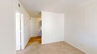 Located at 4040 E Fort Lowell Rd in Tucson, Arizona, this single-floor, one-bedroom, one-bathroom unit offers a practical and well-organized layout designed to maximize every square foot. The space is finished throughout with a clean, neutral color palette of crisp white walls and light-toned textured ceilings, lending a bright and airy feel.

The galley-style kitchen is efficiently arranged with warm wood cabinetry lining both walls, offering ample storage above and below the counters. Light hardwood flooring runs underfoot, and the kitchen is equipped with an electric range, overhead ventilation hood, refrigerator, and a dishwasher alongside a stainless steel sink.

The living area connects seamlessly to the bedroom, both featuring plush beige carpeting that adds warmth and comfort underfoot. The bedroom benefits from a window dressed with horizontal blinds, allowing natural light to filter in while maintaining privacy — with views of the surrounding neighborhood greenery.

The full bathroom features hardwood flooring, a tiled tub and shower combination with a curtain rod, a toilet, and a dark wood vanity with a countertop sink, providing functional storage. A dedicated closet rounds out the unit, offering additional organization space. The overall ambiance is clean, functional, and move-in ready.