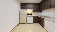 Located at 8 Baron Park Ln in Burlington, MA, this single-floor unit offers a practical and comfortable layout across well-defined living spaces. The kitchen is equipped with dark wood cabinetry extending to the ceiling for generous storage, a tile backsplash, an electric range, a refrigerator, and a basin sink — all set atop easy-care vinyl flooring with a baseboard heating unit nearby. The living and sleeping areas feature neutral wall-to-wall carpeting and crisp white walls, creating a bright and adaptable canvas. Natural light filters in through sliding windows that frame views of surrounding greenery, lending the space a calm, connected-to-nature feel. A wall-mounted air conditioning unit and baseboard heating ensure year-round comfort. Closet space is provided via bifold-door closets integrated into the layout. The bathroom is finished with classic white square tile surrounding a full tub-shower combination, a standard toilet, a vanity sink, and a warm-toned mosaic tile floor that adds a subtle decorative touch. The overall floor plan, as seen in the dollhouse view, presents a compact yet efficiently organized single-level space suited for everyday living in the Burlington, Massachusetts area.