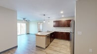 This single-floor, 3-bedroom, 2-bathroom home offers a thoughtfully designed layout that balances functionality and comfort. The open-concept kitchen is a standout feature, showcasing rich dark-wood cabinetry, light granite countertops, stainless steel appliances, and a peninsula with pendant lighting overhead — ideal for both cooking and casual dining. Light wood-look flooring runs consistently throughout the home, tying each space together seamlessly.

The living room is bright and open, with a ceiling fan and sliding glass doors that lead out to a private balcony, offering pleasant views of surrounding trees and greenery. Each of the three bedrooms is well-sized, with the primary bedroom featuring its own walk-in closet with built-in shelving and hanging rods. Additional bedrooms include closets with hanging storage and windows that bring in natural light.

The two bathrooms are clean and modern in design, with one featuring a walk-in shower enclosed by sliding glass doors and a vanity with dark wood cabinetry. A dedicated hallway connects the bedrooms, providing a practical flow throughout the home. Overall, the space presents a neutral, move-in-ready aesthetic with consistent finishes and ample storage throughout.