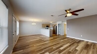 This single-floor residence offers a thoughtfully designed open-concept layout that seamlessly connects the living and kitchen areas. Warm wood-look flooring runs consistently throughout the entire space, lending a cohesive and contemporary feel to every room.

The expansive living area is bathed in natural light from well-positioned windows and is complemented by ceiling fans that provide both comfort and style. An elegant chandelier adds a refined touch to the dining area. The open-concept kitchen features a breakfast bar peninsula, light-toned cabinetry, light-colored countertops, and a full suite of stainless steel appliances including a refrigerator, range, and over-the-range microwave. The kitchen flows naturally into the living space, making it ideal for both everyday living and entertaining.

The bedrooms are generously proportioned, each equipped with ceiling fans and natural light from windows. Ample closet storage is also available. The primary bathroom includes a stylish gray vanity with a quartz-style countertop, a large mirror, and a shower-tub combination. A second full bathroom also features a shower-tub combo and matching light-toned flooring. Clean, neutral wall tones throughout create a bright and inviting atmosphere.