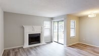 Located at 1600 Winters Creek Dr in Atlanta, Georgia, this single-story residence offers a clean, modern aesthetic enhanced by consistent wood-look luxury vinyl plank flooring throughout. The spacious living room serves as the heart of the home, highlighted by a white-mantled fireplace that adds a classic focal point to the room. Multiple windows dressed with horizontal blinds invite natural light, while a sliding glass door opens directly onto a private balcony, seamlessly connecting indoor and outdoor living. The textured ceilings complement the neutral gray and beige tones found throughout the space.

The galley-style kitchen is well-appointed with white cabinetry, light quartz-style countertops, a gray subway tile backsplash, and stainless steel appliances including a refrigerator and electric range. A window above the sink brings in additional natural light.

The bedrooms are generously sized, each featuring the same LVP flooring and windows that allow for natural light and outdoor views. The bathrooms offer tub-shower combinations with white tile surrounds, vanities with storage, and coordinating flooring. A dedicated in-unit laundry area houses a full-size washer and dryer side by side, providing added everyday convenience.