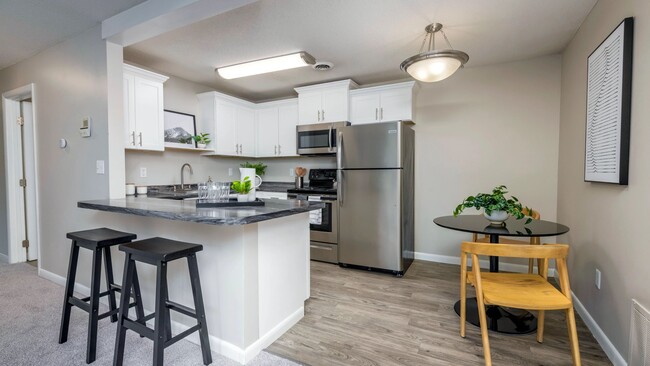 Discover kitchen elegance at Welby Park Estates, where the open concept living seamlessly connects with a welcoming dining area graced by an inviting light fixture, and an elegant breakfast bar for extra seating. - Welby Park Estates