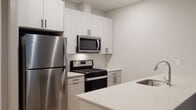 This well-appointed multi-story residence spans three floors and showcases a thoughtfully designed interior with modern finishes throughout. The kitchen is outfitted with stainless steel appliances, including a gas range, over-the-range microwave, and refrigerator, complemented by crisp white shaker cabinetry with matte black hardware, white quartz countertops, and a classic subway tile backsplash. Light wood-tone flooring runs through the kitchen and main living areas, adding warmth to the contemporary aesthetic.

The bedrooms are generously sized, each featuring plush carpeting, neutral-toned walls, and large windows fitted with blinds that invite natural light while offering views of the surrounding neighborhood. One bedroom includes a spacious walk-in closet with wire shelving spanning multiple walls, providing ample storage.

The bathrooms are finished to a high standard, featuring wood-look tile flooring, neutral stone-effect wall tiles with herringbone accent inlays, and light wood-tone vanities with white countertops and matte black hardware. One bathroom offers a sliding glass walk-in shower, while another includes a full soaking tub with overhead shower. A convenient half bath with a single vanity and mirror rounds out the home's bathroom offerings.