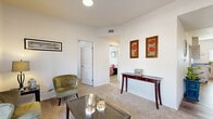 Located in Yuma, Arizona, this single-story, 2-bedroom, 2-bathroom residence offers a thoughtfully designed layout across a comfortable footprint. The open-concept kitchen is outfitted with light wood cabinetry, dark countertops, stainless steel appliances including a refrigerator and dishwasher, and wood-look flooring — all illuminated by a window that invites natural light. A dining area with bar-style seating adjoins the kitchen for convenient everyday living. The residence features two distinct living areas, both carpeted and bright, with large glass doors that bring in abundant natural light and provide outdoor views. One living space flows seamlessly into a secondary room currently used as an exercise or home office area. The primary bedroom includes a ceiling fan, plush carpet, and sliding glass door access to an outdoor space with exterior views. The second bedroom is cozy and well-lit, featuring a window and ceiling fan. Both bathrooms are finished with extended vanities, dark countertops, light wood cabinetry, large mirrors, and durable wood-look flooring. A connecting hallway ties the layout together efficiently, providing easy access throughout the home. The overall ambiance is clean, bright, and functional — well-suited for comfortable living in the Yuma desert climate.