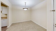 Located in Columbus, GA, this single-floor, 3-bedroom, 2-bathroom home offers a practical and comfortable layout designed for everyday living. The kitchen is a standout feature, fitted with white cabinetry, light countertops, black appliances including an electric range and refrigerator, and wood-look flooring that extends into the adjoining areas. A dedicated dining room with crown molding and a pendant light fixture provides a defined space for meals. The three bedrooms are finished with neutral carpet and cream-toned walls, creating a calm and versatile backdrop. The spacious primary bedroom includes crown molding and a ceiling fan, while secondary bedrooms feature ample closet space with bifold doors and rod-and-shelf storage systems. Natural light filters in through windows with garden views, adding a welcoming quality to the living spaces. Both bathrooms are finished with wood-look flooring, white vanities, and full tub-shower combinations equipped with curtain rods and grab bars. A connecting hallway with ceiling lighting ties the layout together efficiently. Crown molding details appear throughout several rooms, adding a refined touch to the home's overall aesthetic.