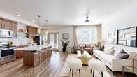 This thoughtfully designed 2-bedroom, 2-bathroom residence features a single-floor open-concept layout that seamlessly connects the kitchen, dining, and living areas. The kitchen is a standout, showcasing warm wood cabinetry, stainless steel appliances, white tile backsplash, quartz countertops, and a large center island with bar seating beneath stylish pendant lighting. Wood-look flooring flows throughout the main living area, where a ceiling fan and large windows invite generous natural light and outdoor views. The living room offers a bright, welcoming atmosphere with ample space for comfortable seating arrangements. The primary bedroom is generously sized, featuring plush carpet, a large window, and direct access to a dedicated walk-in closet with built-in hanging rods. The second bedroom is well-proportioned with carpet flooring and a bright window. Both bathrooms are finished with wood-toned vanities, quartz countertops, undermount sinks, large mirrors, and wood-look tile flooring, maintaining a consistent modern aesthetic. A dedicated entrance and additional closet provide practical storage. The overall ambiance is clean, contemporary, and bright, with a cohesive neutral palette and modern fixtures throughout.