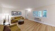 Located at 45 Tamal Vista Blvd in Corte Madera, CA, this single-floor, two-bedroom, one-bathroom residence offers a clean, modern aesthetic throughout. Light wood flooring flows seamlessly across every room, lending a bright and cohesive feel to the entire space. The open-concept living area is generously proportioned, featuring a wall-mounted flat-screen TV, ample room for seating, and a smooth transition into the dining area. The kitchen is efficiently designed with white cabinetry, quartz countertops, a subway tile backsplash, and industrial-style open shelving, creating a functional yet stylish workspace. The spacious primary bedroom benefits from natural light through plantation-shuttered windows, a mirrored sliding closet, and wall-mounted bedside lighting. The second bedroom is equally well-lit, featuring additional plantation shutters and its own closet. A hallway connects the bedrooms to three closets for ample storage. The full bathroom is finished with classic white subway tile surrounding the shower/tub combo, complemented by a granite-topped vanity and chrome fixtures. Crisp white walls and understated décor throughout contribute to the home's calm and welcoming ambiance.
