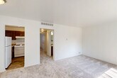 Located at 16651 E 12 Mile Rd in Roseville, Michigan, this one-bedroom, one-bathroom unit offers a thoughtfully organized single-floor layout. The open combined living and dining area is bright and welcoming, featuring light-toned carpeting, clean white walls, and vaulted ceilings that enhance the sense of openness. Large windows with vertical blinds allow generous natural light to fill the space. The kitchen is well-appointed with rich, warm-toned wood cabinetry, light stone-look countertops, a gas range, and a stainless steel sink, complemented by wood-look flooring for easy maintenance. A hallway connects the main living areas to the private bedroom, which is comfortably sized and carpeted, benefiting from multiple windows that bring in additional natural light. The bedroom includes a dedicated closet for ample storage. The full bathroom features wood-look tile flooring, a vanity with matching cabinetry and stone-look countertop, and a full tub/shower combination. Additional practical features include an in-unit laundry area, providing everyday convenience. The overall design maintains a clean, neutral aesthetic throughout, creating a functional and comfortable living environment.