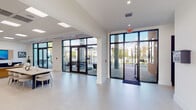 Located in Homestead, Florida, this well-appointed fitness center offers a comprehensive workout environment designed to motivate and accommodate a wide range of exercise routines. The single-floor gym features an open, spacious layout with a clean, contemporary aesthetic defined by light-toned flooring, a drop ceiling with flush panel lighting, and floor-to-ceiling windows along one wall that flood the space with abundant natural light and views of the surrounding outdoors.

The cardio zone is extensively equipped with a row of treadmills, elliptical trainers, and cycling machines, all positioned to face the large windows and wall-mounted flat-screen televisions. Full-length mirrors line one wall, enhancing the sense of openness and allowing users to monitor their form during workouts. The strength training area features multiple Hoist cable machines and selectorized resistance equipment, offering targeted muscle group training options.

Bold, large-scale motivational typography in striking gold lettering adorns the charcoal feature wall, with phrases such as "Push Yourself" and "The Pain You Feel Today Will Be the Strength You Feel Tomorrow," creating an energizing atmosphere. Additional amenities include sanitation stations with wipe dispensers and waste receptacles positioned throughout the space. The gym's bright, clean design and well-organized layout make it a functional and inspiring facility for daily fitness use.