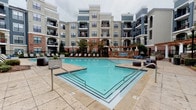 Located at 415 Armour Dr in Atlanta's vibrant 30324 corridor, this CWS Apartment Homes community showcases a thoughtfully designed outdoor amenity area that serves as the centerpiece of the property. The expansive resort-style pool is the focal point, featuring a generously sized swimming area with a gradual entry, surrounded by a broad stamped concrete deck lined with lounge chairs — ideal for relaxation and recreation.

Framing the pool area is a classic architectural backdrop of multi-story residential buildings constructed with a refined blend of brick and neutral-toned siding, accented by balconies and arched detailing that lend a sophisticated character to the community.

A pergola-covered outdoor kitchen and grilling station adds significant functionality to the space. Outfitted with a full-size KitchenAid grill and stone-clad counter surfaces, the area is designed for outdoor entertaining. White classical columns support the rich wood-beam pergola overhead, creating a shaded, welcoming atmosphere.

Connecting these amenities is a beautifully laid brick paver pathway that winds through manicured landscaping, offering additional seating areas with bistro-style tables and chairs beneath the pergola. Wrought-iron fencing and gated access provide both security and a polished aesthetic. The overall ambiance is one of upscale, resort-inspired outdoor living in the heart of Atlanta.