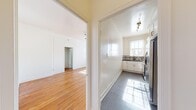 This thoughtfully designed 1-bedroom, 1-bathroom residence offers a practical and comfortable single-floor layout. The spacious primary bedroom is a standout feature, boasting soaring ceilings, warm hardwood flooring, and abundant natural light streaming through multiple windows. A ceiling fan adds functionality, while a classic cast-iron radiator speaks to the unit's character. The bedroom also includes a built-in closet for convenient storage.

The kitchen is stylishly updated, featuring white shaker cabinets with gold hardware, dark granite countertops, and an eye-catching black-and-white patterned tile backsplash. Stainless steel appliances, including a gas range and microwave, complete the modern, functional space. Large gray tile flooring and a window overlooking the surroundings add brightness and polish.

The bathroom maintains a clean, classic aesthetic with white tile wainscoting, a pedestal sink, a soaking tub, and large-format slate tile flooring. Natural light filters through a window with blinds, enhancing the airy feel.

A welcoming entrance and hallway connect all areas seamlessly, with rich hardwood flooring carrying through the living spaces. The overall ambiance is bright, clean, and full of timeless charm.