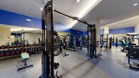Located at 824 W Route 66 in Flagstaff, Arizona, this fitness center offers a generously sized, single-floor layout divided into two dedicated exercise rooms connected by a hallway. The facility is designed to accommodate a comprehensive range of workout modalities, making it suitable for both cardio-focused and strength-training routines.

The main exercise room features rubber flooring and is outfitted with an extensive array of Matrix-brand strength machines, cable systems, free weights, dumbbells, and adjustable benches. Floor-to-ceiling mirrors line the walls, amplifying the sense of space, while bold blue accent walls add a dynamic visual energy. Recessed lighting and ceiling fans provide a comfortable training environment throughout.

A dedicated cardio zone houses a full row of Matrix treadmills and elliptical trainers, each equipped with individual screens. This area benefits from recessed ceiling lighting and a sloped ceiling detail that adds architectural character.

The second exercise room features warm hardwood flooring and serves as a functional training and group fitness space. It includes battle ropes, a suspension training rig, medicine balls, a heavy bag, and spin bikes. Storage lockers, wall-mounted mirrors, and ceiling fans complete the space. Together, the two rooms deliver a well-rounded, professional-grade fitness facility.