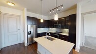 Located at 3535 Bluffs Ln in Grapevine, TX, this single-floor residence offers a contemporary design with a cohesive blend of dark and light finishes throughout. The kitchen serves as a centerpiece of the home, showcasing rich dark espresso cabinetry that extends floor to ceiling, light quartz countertops, a subway tile backsplash, and a full suite of stainless steel appliances including a refrigerator with ice maker, built-in microwave, and electric range. A central island with an undermount sink and pendant lighting above adds both functionality and style, while track lighting and rich hardwood flooring complete the space. The open layout connects the kitchen seamlessly to the living area, which also features hardwood floors and an abundance of neutral wall tones. Bedrooms are finished with plush carpet and include a ceiling fan with lighting, as well as window blinds for privacy and natural light control. The walk-in closet is outfitted with built-in shelving, hanging rods, and cubbies for organized storage. The bathroom features large-format tile flooring, a soaking tub with tiled surround and built-in niche, a dark vanity with ample drawer storage, and a wide mirror with overhead lighting — delivering a clean, modern aesthetic throughout.