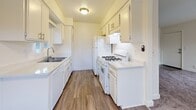 Located at 700 W Avenue I in Lancaster, CA, this two-bedroom, two-bathroom residence offers a thoughtfully laid-out single-floor plan designed for comfortable everyday living. The open living area is highlighted by plush carpeting, a ceiling fan, a textured ceiling, and a classic fireplace that serves as a natural focal point. Sliding glass doors lead to a private balcony overlooking the community pool and courtyard, bringing in natural light and pleasant outdoor views. The galley-style kitchen is efficiently designed with white cabinetry, light quartz-style countertops, a stainless steel sink, and white appliances including a gas range and refrigerator, all set atop wood-look flooring. The primary bedroom is a comfortable retreat featuring mirrored sliding closet doors and direct access to an en-suite bathroom. The second bedroom also features carpeting and a sliding double-door closet. Both bathrooms are finished with white cabinetry, light countertops, and tub-shower combinations with wood-look flooring. A hallway connects the rooms, adding to the practical flow of the layout. The residence is part of a well-maintained community with shared amenities including a pool and landscaped common areas.