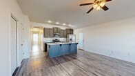 Located at 5309 Overcrest Ave in Springdale, Arkansas, this single-story home offers a thoughtfully designed open-concept layout with consistent wood-look flooring running throughout. The kitchen serves as a central focal point, showcasing rich dark-stained cabinetry, granite countertops, and a full suite of stainless steel appliances including a gas range, microwave, and refrigerator with ice maker. A generously sized island with a built-in sink and striking blue cabinetry anchors the space, providing both additional prep area and seating. The kitchen flows seamlessly into the living area, which features a ceiling fan with light kit and a large window that invites natural light into the room. Bedrooms are well-proportioned, each equipped with ceiling fans and walk-in closets featuring built-in shelving and hanging rods. A spacious walk-in closet with multi-tier shelving is also present. The bathroom includes dark-stained vanity cabinetry, granite countertops, a large mirror, and a tub-shower combination. A dedicated laundry room accommodates full-sized side-by-side washer and dryer units, adding everyday practicality to the home's functional layout.