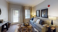Located at 11100 Beckstone Way in Wake Forest, NC, this single-floor residence offers a thoughtfully designed layout that balances comfort and style. The living room welcomes natural light through multiple windows dressed with elegant drapes, and features rich hardwood flooring, crown molding, and direct access to an outdoor area via a glass-paneled door. Adjacent to the living space, the dining area is defined by a pendant light fixture, coordinating crown molding, and the same warm hardwood floors, creating a seamless flow between entertaining spaces. The kitchen is outfitted with dark espresso cabinetry, granite-style countertops, and black appliances including a refrigerator, range, and built-in microwave, all complemented by hardwood flooring. The primary bedroom offers plush carpeting, a ceiling fan, and generous wall space, while a second bedroom mirrors the comfortable aesthetic with soft carpet, a ceiling fan, and bright windows. The bathroom features dark vanity cabinetry with a bold marble-style countertop, tile flooring, and well-lit mirror above the single-basin sink. Neutral tones and consistent finishes throughout give the home a cohesive, polished ambiance.