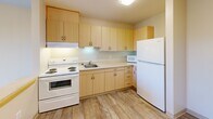 Located in the Rainier Beach neighborhood of Seattle, WA, this one-bedroom, one-bathroom unit on the third floor offers a practical and well-organized layout. The open-concept living area seamlessly combines the kitchen, dining, and living spaces into one cohesive zone. The kitchen is equipped with light maple cabinetry, ample upper and lower cabinet storage, a full-size refrigerator, electric range with oven, microwave, and a single-basin sink — all set against wood-look flooring that extends through the entry and kitchen areas. A peninsula counter provides a natural division between the kitchen and the carpeted living and dining space, which receives natural light through a large window. The bedroom is a well-proportioned, carpeted retreat featuring a built-in closet with bifold doors and a window overlooking the surrounding area. Two closets provide additional storage throughout the unit. The bathroom features wood-look tile flooring, a shower/tub combo, and accessibility-friendly grab bars along the walls. The unit's clean, neutral color palette of warm beige tones creates a bright and welcoming atmosphere throughout.
