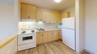 Located in the Rainier Beach neighborhood of Seattle, WA, this one-bedroom, one-bathroom unit on the third floor offers a practical and well-organized layout. The open-concept living area seamlessly combines the kitchen, dining, and living spaces into one cohesive zone. The kitchen is equipped with light maple cabinetry, ample upper and lower cabinet storage, a full-size refrigerator, electric range with oven, microwave, and a single-basin sink — all set against wood-look flooring that extends through the entry and kitchen areas. A peninsula counter provides a natural division between the kitchen and the carpeted living and dining space, which receives natural light through a large window. The bedroom is a well-proportioned, carpeted retreat featuring a built-in closet with bifold doors and a window overlooking the surrounding area. Two closets provide additional storage throughout the unit. The bathroom features wood-look tile flooring, a shower/tub combo, and accessibility-friendly grab bars along the walls. The unit's clean, neutral color palette of warm beige tones creates a bright and welcoming atmosphere throughout.